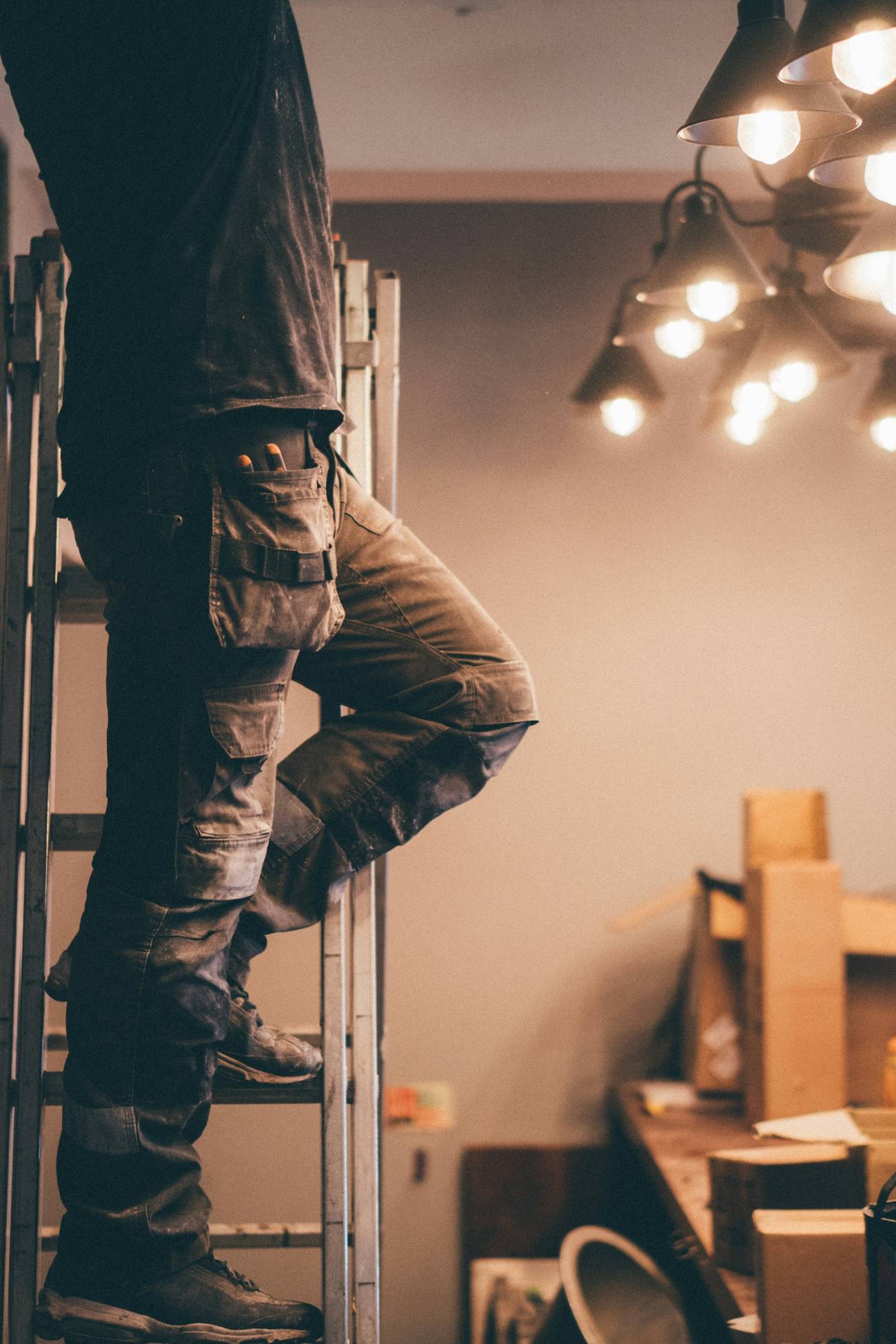 Electrician on a ladder working on ceiling light fixtures