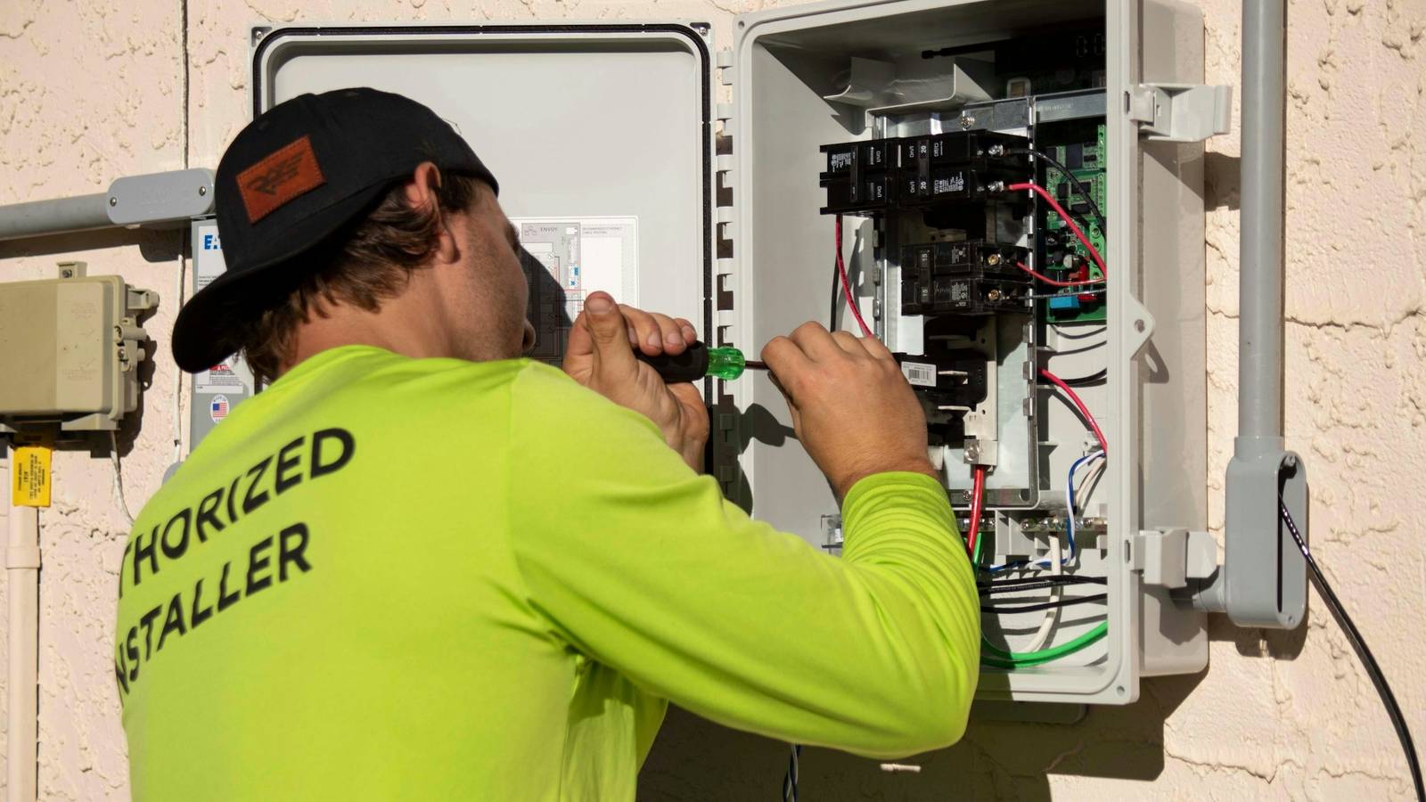 Electrician working inside an electrical panel on the side of a home